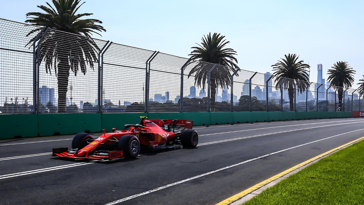 Formula 1 car driving on a palm-lined street circuit, with a city skyline in the background.