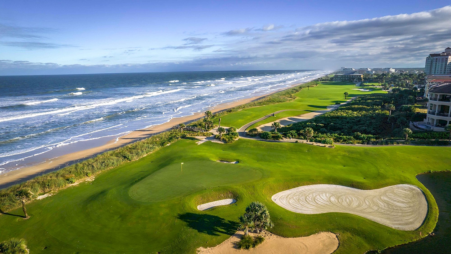 A breathtaking view of Hammock Beach Golf Resort's oceanfront golf course with lush greenery and scenic ocean waves in the background.