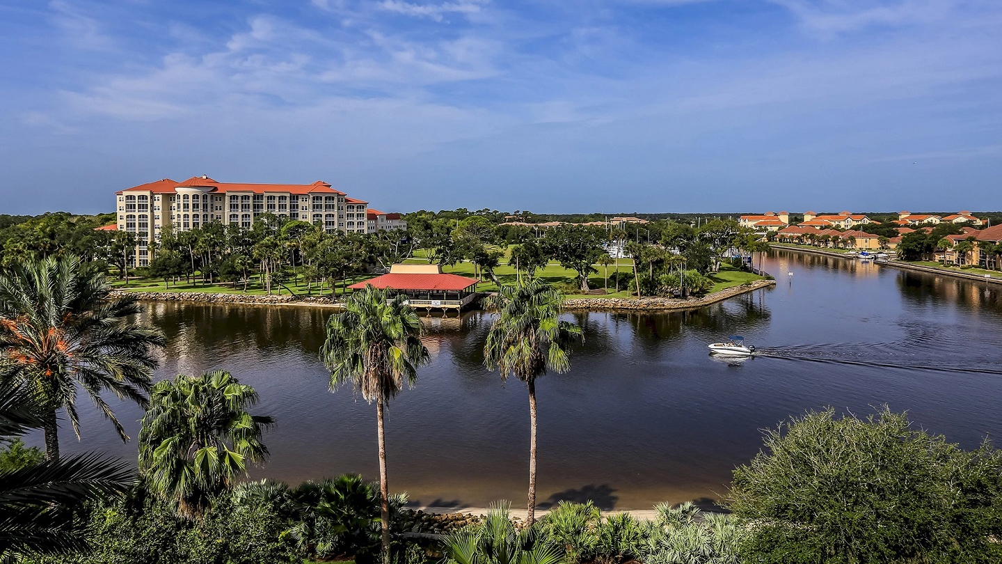 A serene landscape featuring Hammock Beach Golf Resort's luxurious accommodations surrounded by palm trees and tranquil waterways.