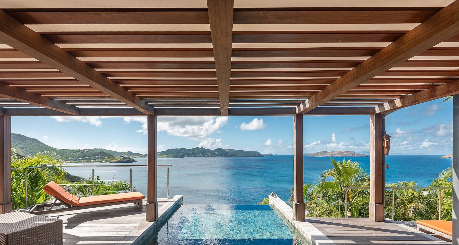 Infinity Pool with Panoramic Ocean Views – A serene infinity pool overlooking the turquoise waters of St. Barths, framed by lush greenery and elegant wooden architecture. A dream getaway for donors.