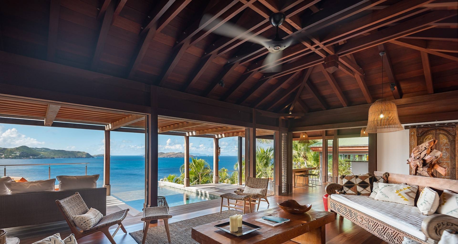 Spacious Open-Air Living Room with Ocean Views – A beautifully designed open-concept living space with high wooden ceilings, stylish furnishings, and seamless indoor-outdoor flow, offering breathtaking ocean views in St. Barths.