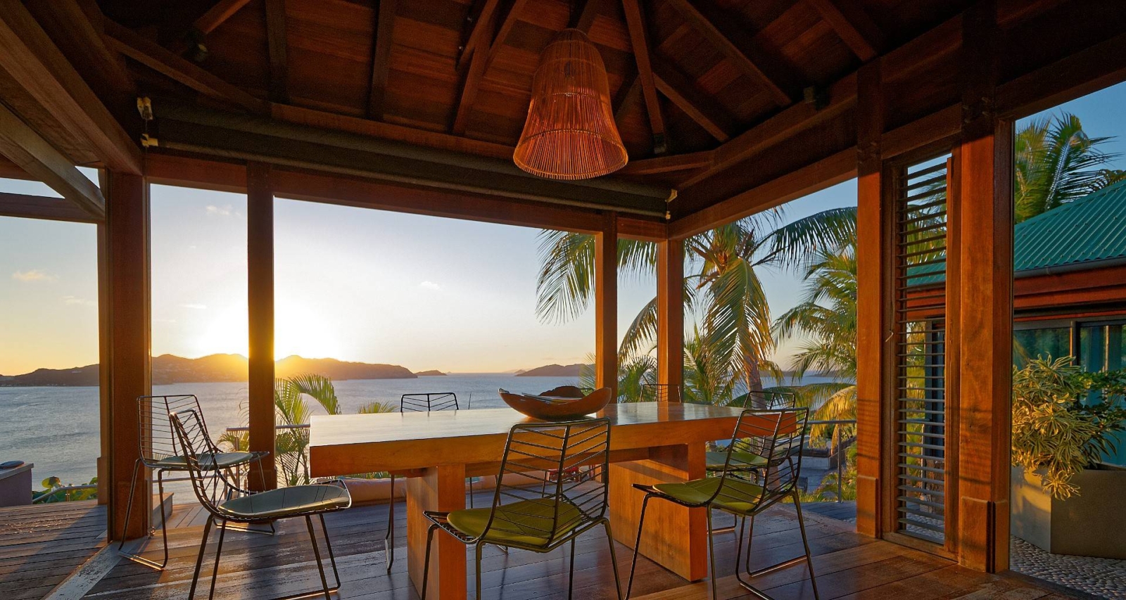 Sunset Dining with Ocean Views – An intimate dining space under a rustic pergola, overlooking the Caribbean Sea at sunset. A luxurious St. Barths experience for charity auction winners.