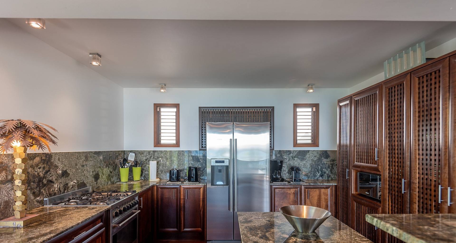 Gourmet Kitchen with Modern Amenities – A fully equipped modern kitchen featuring stainless steel appliances, marble countertops, and wooden cabinetry, blending island charm with upscale comfort in St. Barths.