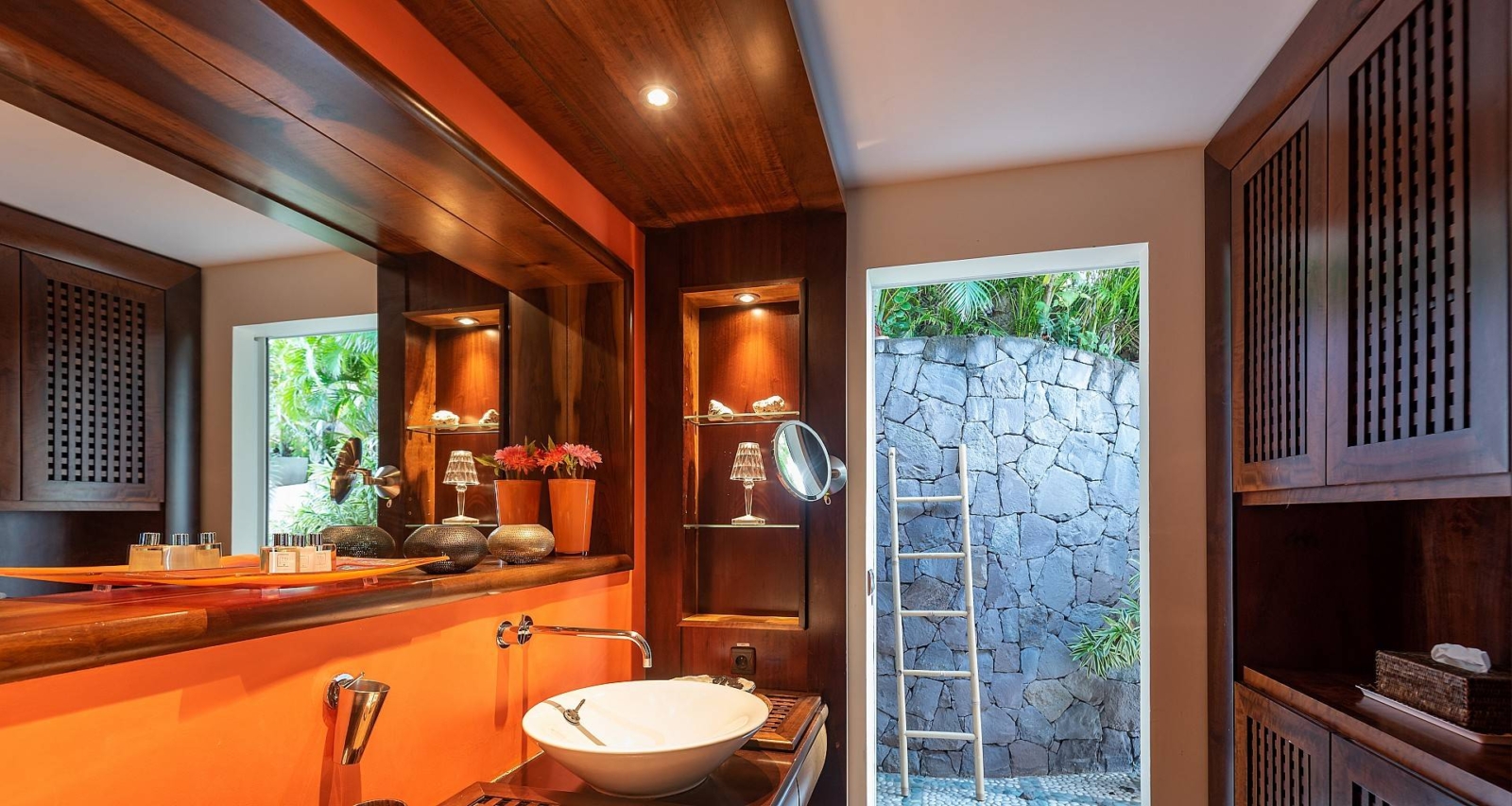 Spa-Inspired Bathroom with Outdoor Access – A tropical bathroom featuring a stone accent wall, vessel sink, and open-air access, creating a relaxing spa-like atmosphere in St. Barths.