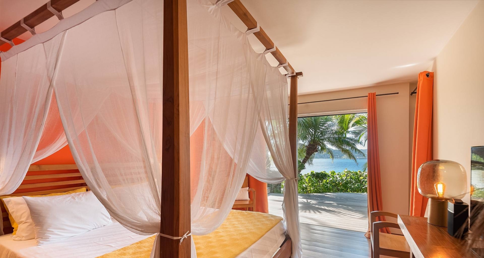 Elegant Bedroom with Private Terrace – A beautifully designed bedroom featuring a four-poster bed, airy white drapes, and direct access to a private terrace with ocean views in St. Barths.