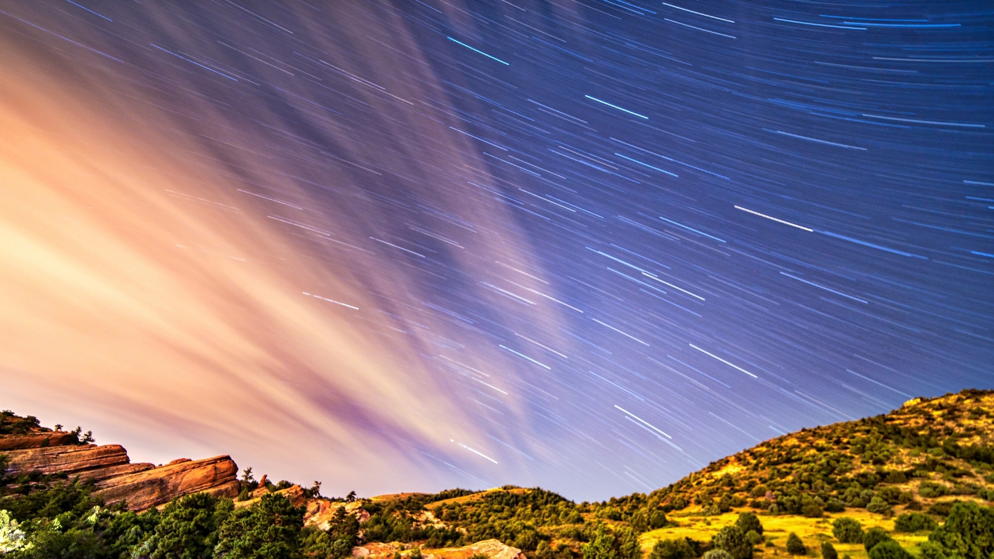 Mesmerizing star trails over Red Rocks Amphitheatre, with the vibrant orange rock formations and dark night sky.