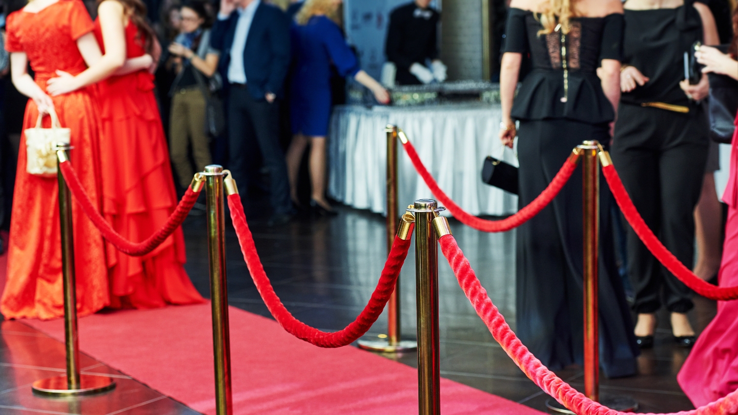 Close-up of a red carpet event with velvet ropes and stylish attendees, capturing Hollywood elegance.