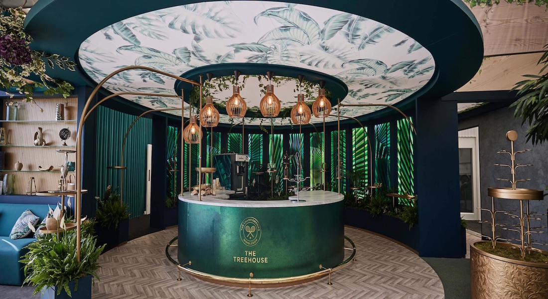 Elegant interior of The Treehouse hospitality lounge at Wimbledon, featuring lush greenery, gold accents, and a premium dining experience.