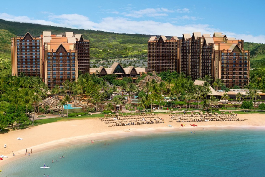 The stunning beachfront view of Aulani Resort with its sprawling buildings and private beach. The turquoise waters and golden sand provide a serene escape.