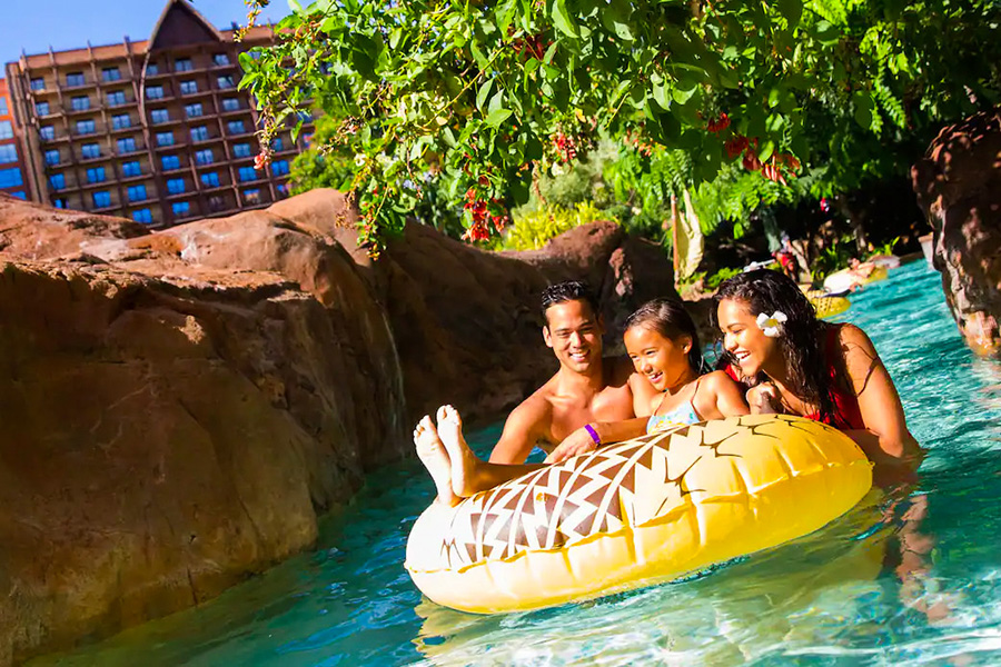 A joyful family experience at the lazy river, surrounded by natural rock formations and lush foliage, with the resort’s iconic architecture in the background.