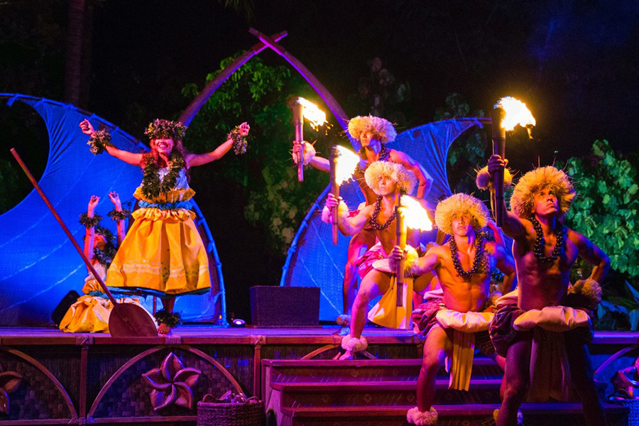 A vibrant luau with traditional Hawaiian dancers and fire performers against a beautifully lit stage, immersing guests in Polynesian culture.