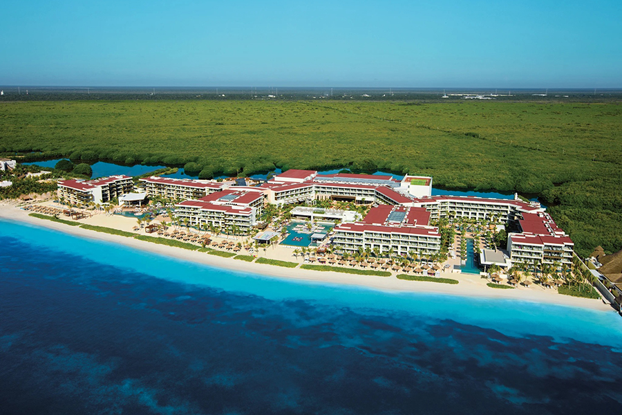 Expansive aerial view of the Breathless Riviera Cancun Resort & Spa, surrounded by lush mangroves and fronting the crystal-clear waters of the Riviera Cancun.