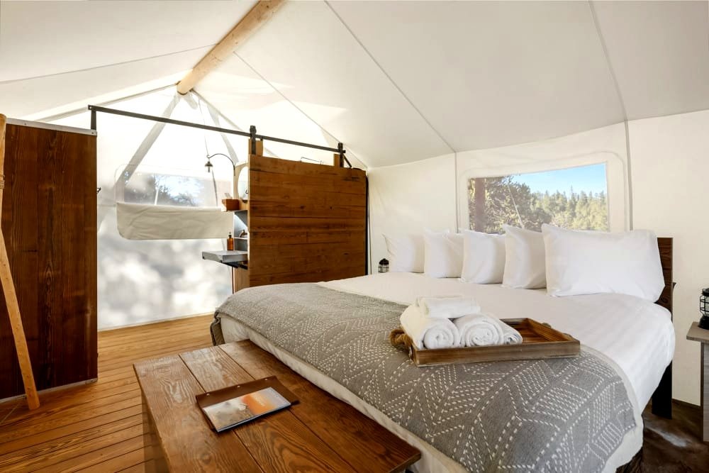 Glamping Tent Interior with King-sized Bed: Inviting king-sized bed inside a deluxe glamping tent featuring a cozy wood-burning stove and en-suite bathroom near Bryce Canyon.