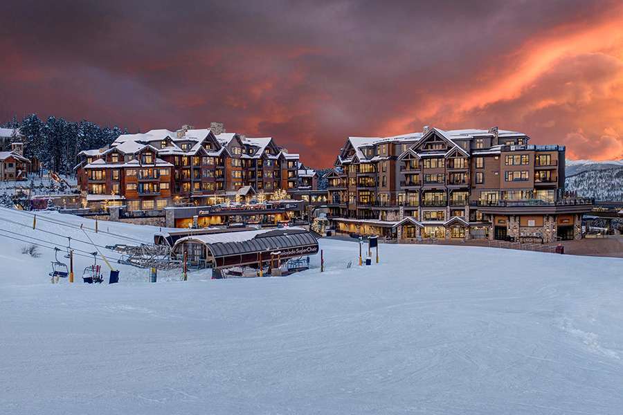 Grand Lodge on Peak 7 illuminated at sunset with a stunning winter landscape and ski lifts in Breckenridge, Colorado.