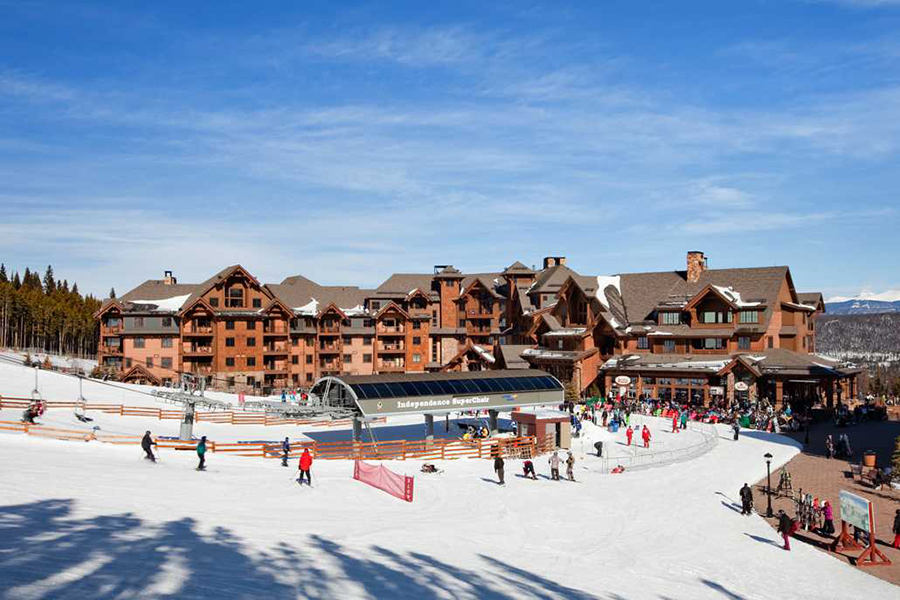 Daytime view of Grand Lodge on Peak 7 with skiers and Independence SuperChair ski lift in Breckenridge, Colorado.