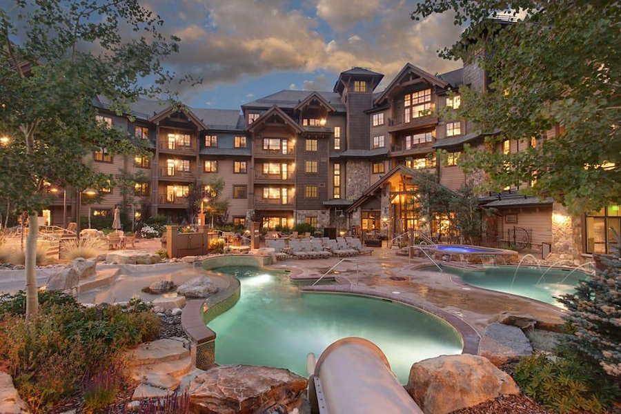 Heated outdoor pools and hot tubs at Grand Lodge on Peak 7, glowing against a winter evening backdrop.