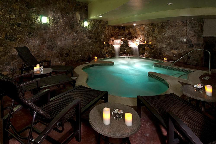 Luxurious indoor spa area at Grand Lodge on Peak 7 with warm lighting, cascading waterfall, and cozy seating.