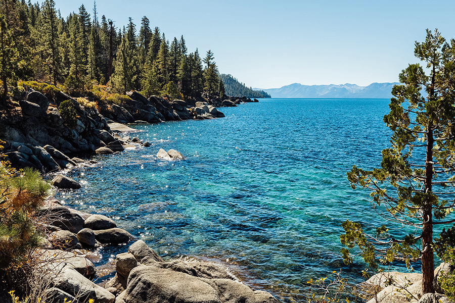 Chimney Beach at Lake Tahoe, featuring crystal-clear blue waters, rocky shoreline, and scenic pine trees.