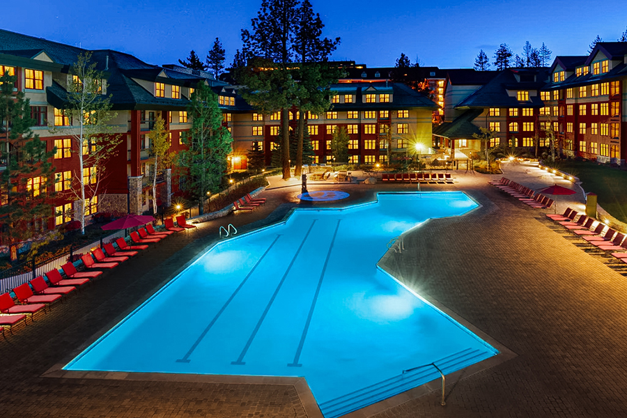 Outdoor swimming pool at Marriott’s Timber Lodge in Lake Tahoe, lit up at night with lounge chairs and alpine ambiance.