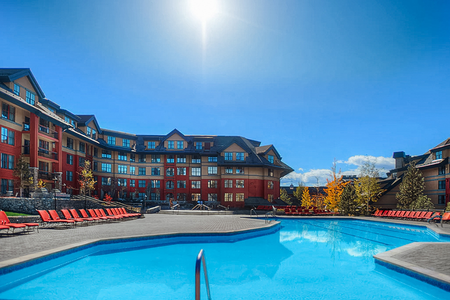 Bright and sunny poolside view at Marriott’s Timber Lodge, with red lounge chairs and a blue sky in Lake Tahoe.