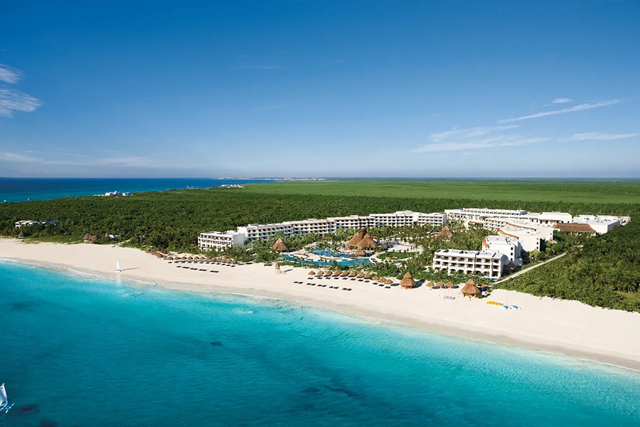 A stunning aerial view of Secrets Maroma Beach Riviera Cancun with its expansive white sandy beach and turquoise Caribbean waters.