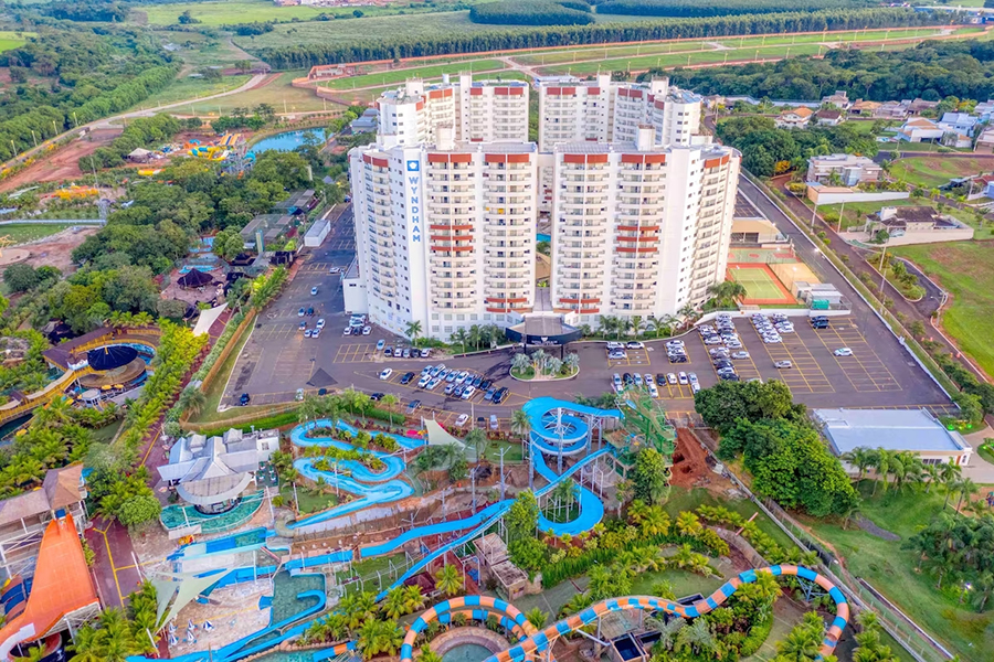 Vibrant family-friendly resort featuring a towering modern hotel surrounded by lush greenery, an expansive water park with thrilling slides, and a variety of outdoor attractions, offering endless fun and relaxation.